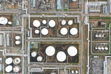 Aerial top down view over oil refinery and power plant with many storage tanks and pipelines.