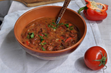 Spicy red beans. Hot homemade bean soup with tomatoes and peppers in a ceramic bowl.