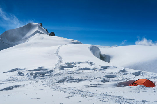 Berelskoe sedlo mountain climbers camp. Red tentin the snow. View to the Belukha Mountain glaciers. Belukha Mountain area. Altai, Russia.