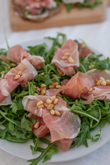Healthy salad with prosciutto, tomato and green leaves