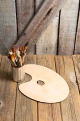 bundle of artist's paintbrush at tin can, blank palette, rusty wooden