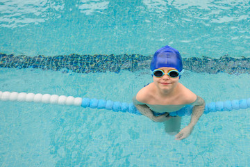 Fototapeta na wymiar top view of a 7-year boy playing and swimming in the swimming pool smiling and laughing
