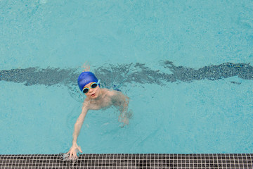 top view of a 7-year boy playing and swimming in the swimming pool