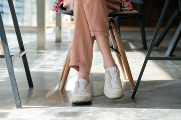 girl teenager legs wearing sneakers sitting at cafe