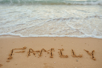 top view FAMILY lettering on the sand of a beach with wave and sunshine