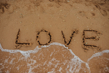 top view LOVE lettering on the beach with wave and sunlight