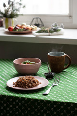 A healthy breakfast: a plate of buckwheat, a salad, a bowl of jam and tea.