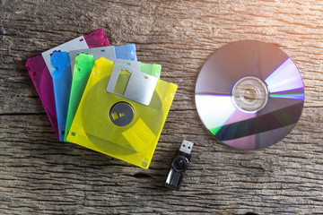 Floppy disk, CD-ROM and Flash drive on wood background.