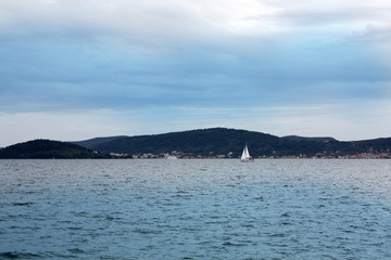 White sailboat in Adriatic Sea with sunset.