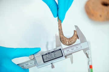 Archaeologist Measuring Ancient Hook with Digital Caliper