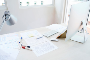 Desk of UI designer or mobile application developer covered with documents and wireframes