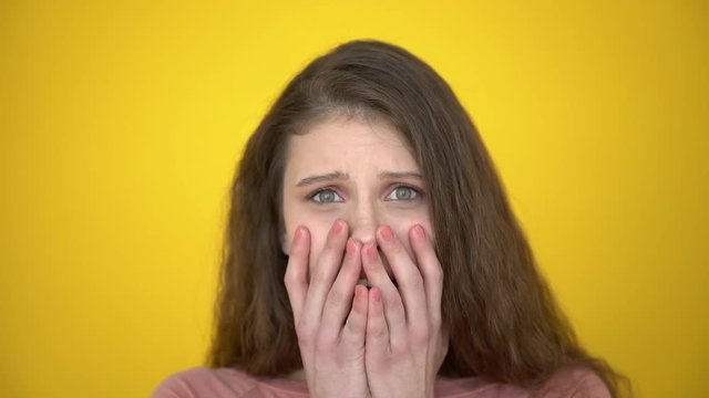 shock, fear, horro. Portrait of young shocked afraid woman teen girl on yellow background in studio. Woman scared and afraid, desperate for something, covering mouth with hands. problems, emotions 4 K
