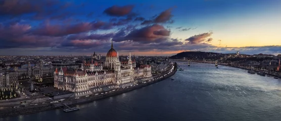 Photo sur Plexiglas Széchenyi lánchíd Budapest, Hongrie - Vue panoramique aérienne du magnifique Parlement illuminé de Hongrie avec le pont à chaînes Szechenyi, le palais royal du château de Buda et les nuages colorés en arrière-plan au coucher du soleil