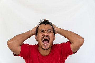 Enraged furious asian man open his mouth and screaming in anger and stress, pulling his hair out with his hand, stand isolated on white background and make grimace closed eyes. Space for text
