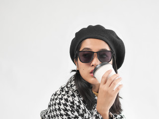 Portrait of Asian woman wearing winter jacket and sitting on vintage brown bag, and drinking coffee cup.
