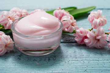 cosmetic creams with pink hyacinth flowers, on old cracked blue table