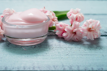 cosmetic creams with pink hyacinth flowers, on old cracked blue table