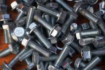 a large number of metal bolts on a wooden desktop