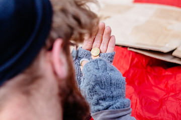 Close up of beard homeless man in eyeglasses looking on hands with different coins sitting on bench...