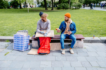 Opposite concept. Handsome beard man sits on bench with coffee and croussant proposing food for...