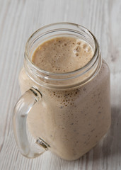 Banana kiwi apple smoothie with chia seeds in a glass jar, low angle view. Close-up.