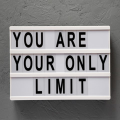 'You are your only limit' words on a light box over gray background, top view. Overhead, from above. Flat lay.