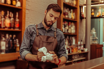 Handsome bartender polishing a glass at the bar