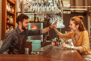 Radiant woman giving a high five to a bar worker