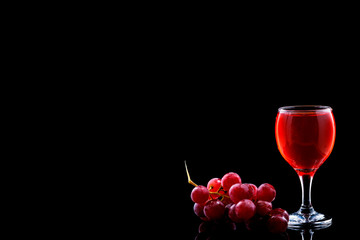 Wine glass and red grapes with drops on blak backgound. Space fot text menu