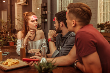 Charming woman wearing white top playing a hedbanz game.
