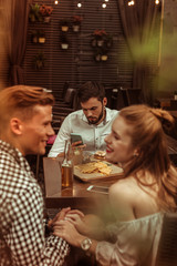 Happy couple flirting while their friend is clicking on phone