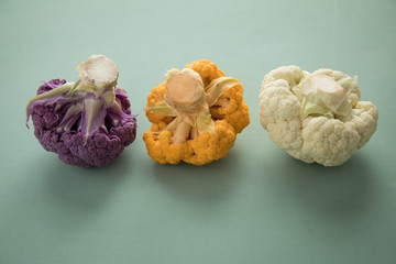 Bunter Blumenkohl in Lila, Orange und Weiß in Reihe auf Pastell Grün Hintergrund