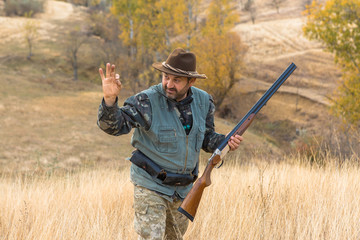 Hunter with a hat and a gun in search of prey in the steppe	