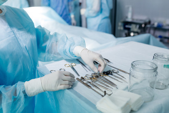 nurse in sterile gloves choosing tool to perform surgery. close up cropped photo.job, profession, occupation