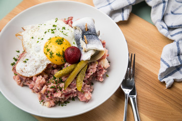 Norddeutscher Hamburger Labskaus mit Rindfleisch Corned Beef, Rote Beete, Kartoffeln, Saure Gurken, Spiegelei und Rollmops auf Teller
