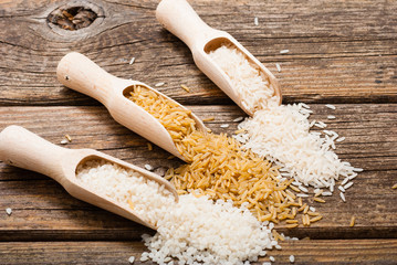 three different types of rice on scoops, old wood table
