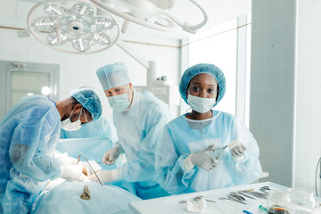 attractive assistant using scissors and looking at the camera while performing operation