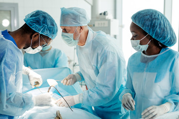 professional multiracial surgons specialize in cutting open the body to heal his patients.