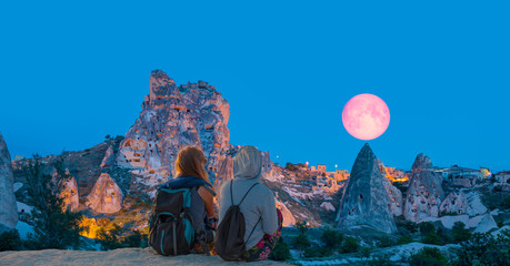 Amazing view of Uchisar castle in Cappadocia at twilight blue hour - Girls watching moonrise at the...
