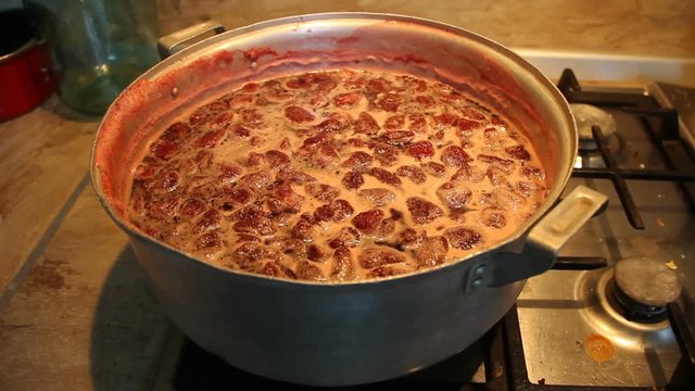 Preparation of strawberry jam. Cook jam. Homemade berry jam gradually boils in a large flat saucepan. Traditional cuisine