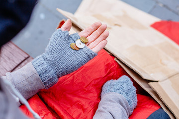Close up homeless man hands with coins in the city streets. Top view. Way of earning money for the...