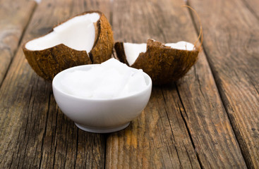 pile of rigid coconut oil on china dish and broken coconut shells, old wood table