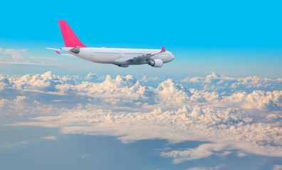 Fototapeta na wymiar Commercial airplane flying above clouds in dramatic sky