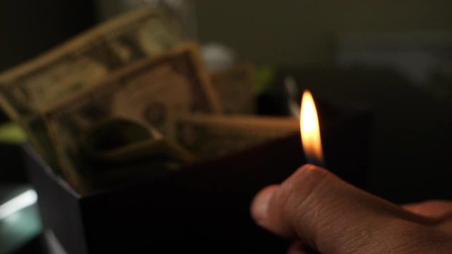 A cigarette lighter emits a flame with dollar bills in a box, money background. Dollars money set With Shallow Dof. Dollars, money close up.