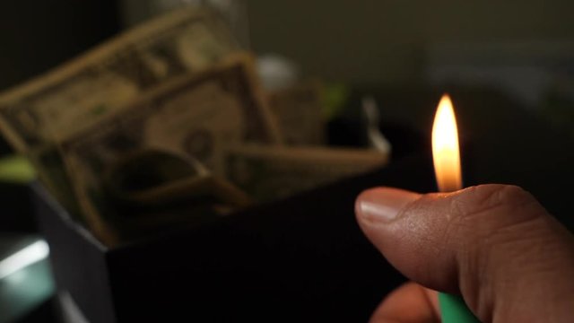 A cigarette lighter emits a flame with dollar bills in a box, money background. Dollars money set With Shallow Dof. Dollars, money close up.