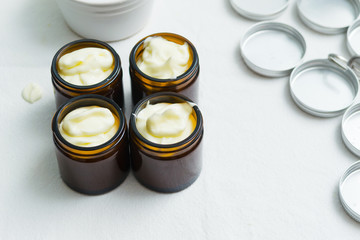 cosmetic lotion cream diy do it yourself ingredients creamer arrangement on white textile cloth top...