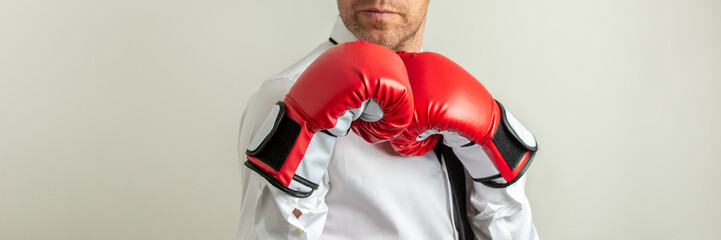 Businessman wearing red boxing gloves in a defensive position