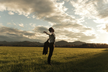 Businessman standing in nature with arms wide open