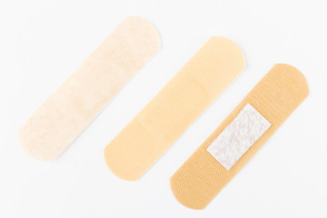 Adhesive plasters of various skin tones from light beige to saturated. A set of adhesive plasters on a white background. Necessary items for summer activities, treatment of wounds, scratches.