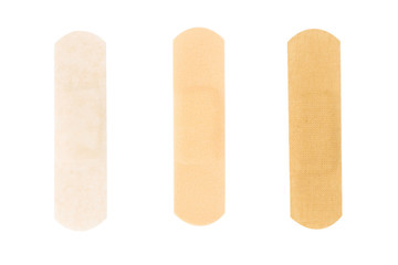 Adhesive plasters of various skin tones from light beige to saturated. A set of adhesive plasters on a white background. Necessary items for summer activities, treatment of wounds, scratches.